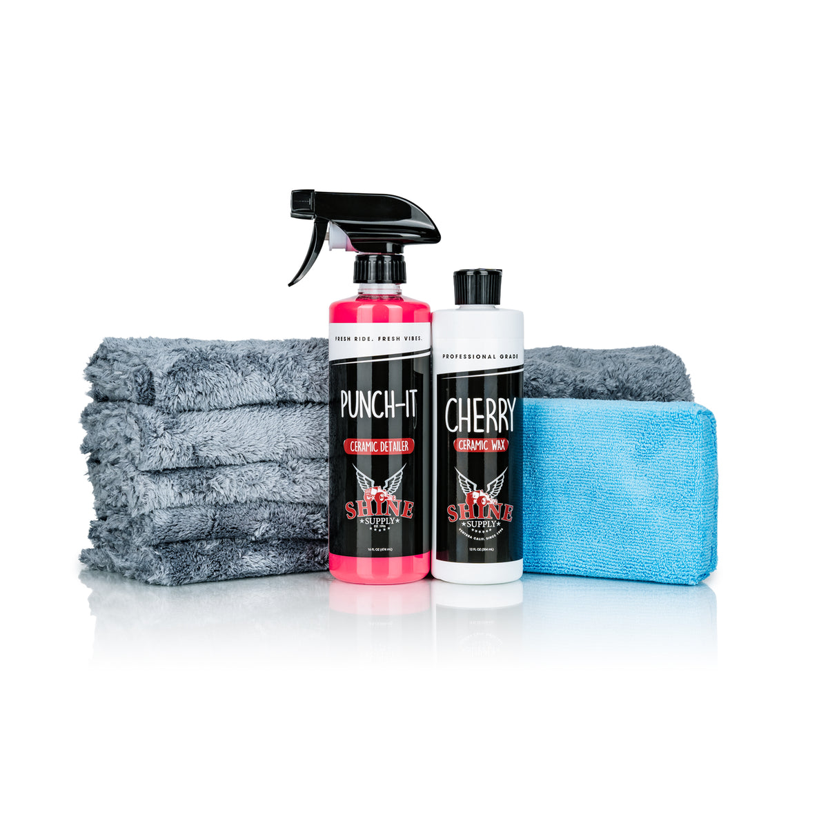 Shine Supply Ceramic Wax Kit with Cherry ceramic wax, Punch-It ceramic detail spray, a blue microfiber applicator pad, and a stack of grey Cosmo plush microfiber towels